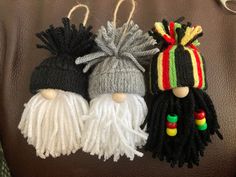 three knitted christmas ornaments hanging on a leather surface