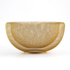 a gold colored bowl is sitting on a white surface with no one in the photo