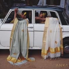 two women are sitting in the back of a white car with yellow and gray scarves