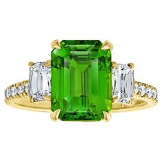 an emerald and diamond ring with three diamonds on the band, set in yellow gold