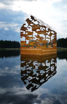 a wooden structure floating on top of a lake under a cloudy sky with trees in the background