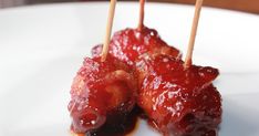 two skewered meats covered in ketchup on a white plate with toothpicks