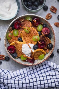 a bowl filled with fruit and yogurt on top of a blue checkered napkin