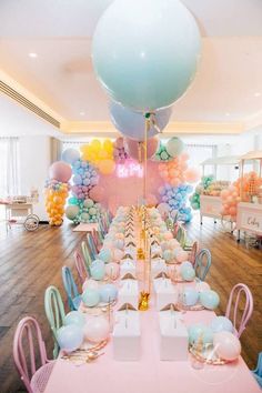 a room filled with lots of balloons and tables covered in pink, blue, and yellow