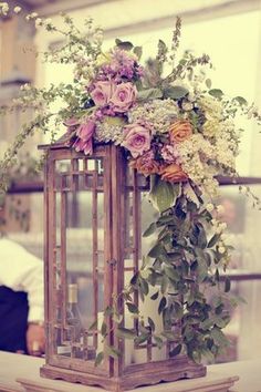 a wooden lantern with flowers and greenery on it