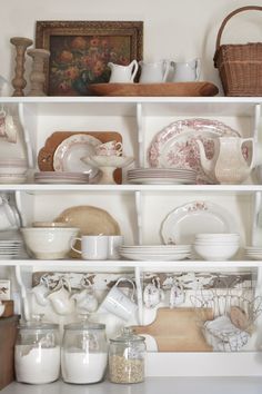 a white shelf filled with dishes and cups