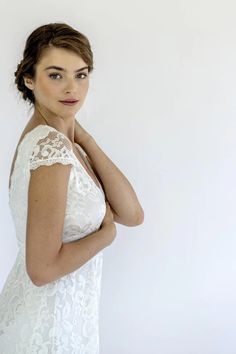 a woman in a white dress posing for the camera with her hand on her shoulder