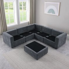 a large gray couch sitting on top of a white rug in front of a window