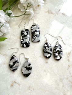 Black and grey polymer clay dangle earrings. Accented with silver leaf and sealed with resin. Hardware is silver plated. This item is handmade and may vary slightly in appearance. Silver Resin Drop Earrings, Gray Ear Wire Earrings For Gift, Gray Drop Earrings For Gift, Nickel-free Silver Resin Earrings, Handmade Silver Polymer Clay Jewelry, Nickel Free Silver Polymer Clay Earrings, Silver Polymer Clay Earrings For Gift, Silver Resin Earrings As A Gift, Silver Resin Earrings For Gift