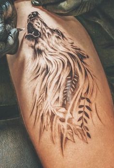 a tattoo on the leg of a person with a wolf head and feathers in it