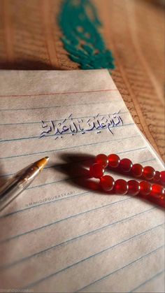 a pen sitting on top of a piece of paper next to a red beaded bracelet