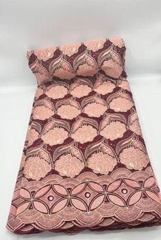 the pink and brown fabric is folded on top of each other, with an intricate design