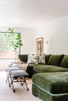 a living room filled with furniture and a large green sectional couch in front of a window