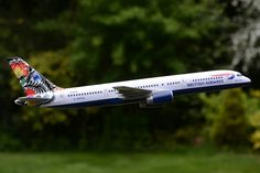 a white and blue airplane with designs on it's wings flying in the air