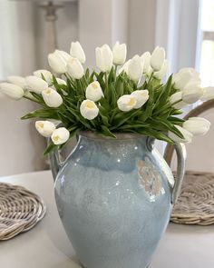 a blue vase filled with white flowers on top of a table