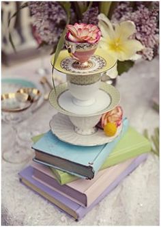 a stack of books sitting on top of a table next to a vase filled with flowers