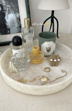 an assortment of perfumes on a tray next to a lamp