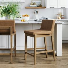 two brown chairs sitting in front of a kitchen counter