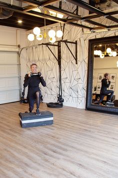 a woman standing on top of a black box in front of a mirror and lights