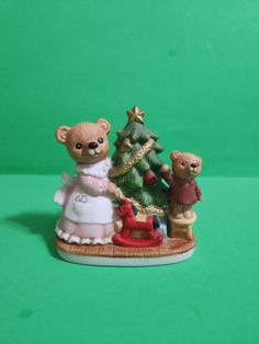 a ceramic figurine of two bears and a christmas tree on a green background