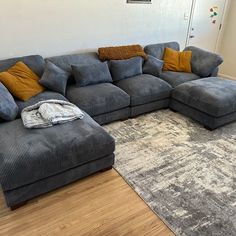 a large gray couch sitting on top of a wooden floor next to a white wall