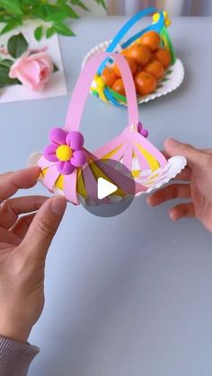 someone is holding a paper flower decoration in front of a plate with fruit on it