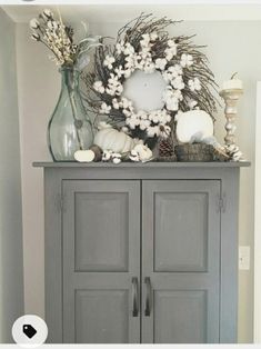 a gray cabinet with a wreath and candles on top