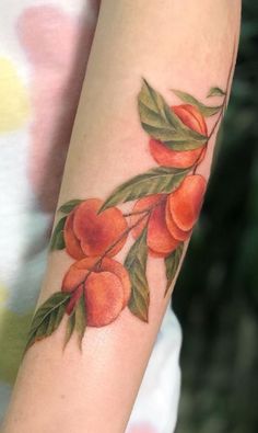 a woman's arm with peachs on it and leaves painted on the arm