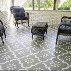 three wicker chairs sitting on top of a porch next to a white brick wall