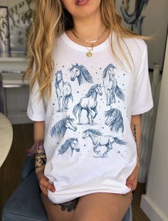 Express your love for horses in this beautiful mystical horse t-shirt!  Want a different design or color? Just let us know and we'll make it happen!  FIT & SIZING: * These soft and lightweight Bella-Canvas unisex t-shirts have just the right amount of stretch, and are made in the USA. * Tees are comfortable and flattering for both men and women. * Please see the size chart in the photos to obtain an accurate size. Measure one of your favorite tees for comparison! * Ladies: These tees are unisex sizes. Your normal size will fit a bit loosely. For a snug fit, order one size down from your normal size. For an oversized fit, size up.  * Though rolled up in some product pictures, sleeves will not come rolled up on delivery. GARMENT FEATURES: * 100% combed and ring-spun cotton (Heather colors co Casual Short Sleeve Tops With Horse Design, White Unicorn Print T-shirt For Summer, Short Sleeve Cotton Top With Horse Design, Casual Cotton T-shirt With Horse Design, Summer White T-shirt With Unicorn Print, Cotton Short Sleeve Top With Horse Design, Casual Short Sleeve T-shirt With Horse Design, Casual Short-sleeved T-shirt With Horse Design, White Unicorn Print Crew Neck Top