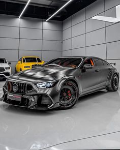 three cars are parked in a garage with grey walls and flooring, while one is black