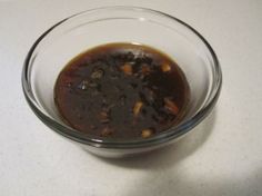 a glass bowl filled with food sitting on top of a white counter next to a knife