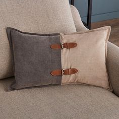 a pillow with two buckles on it sitting on a couch next to a chair