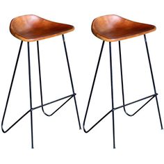 two wooden stools with metal legs and leather seat covers on each side, against a white background