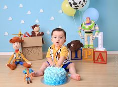 a baby boy sitting on the floor in front of a birthday cake with toy figures