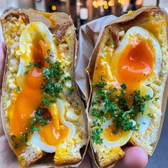 two pieces of bread with an egg and cheese on them, held in someone's hand