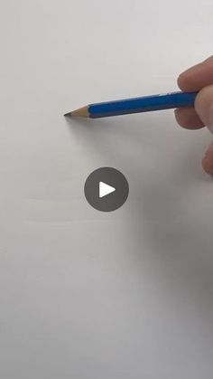 a person holding a pencil in their right hand and writing on paper with the other hand