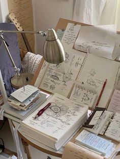 a desk with lots of notebooks on it and a lamp next to the table