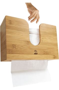 a person's hand reaching into a bamboo tissue dispenser