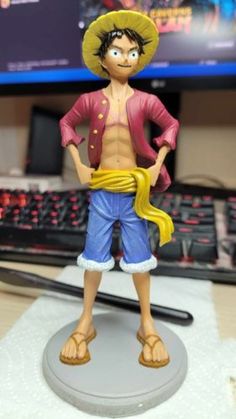 one piece figurine is standing in front of a computer monitor and keyboard, with his hands on his hips