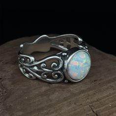 Opal Filigree Ring, Sterling Silver Scroll Ring, Round Lab Opal Cabochon Opal Filigree Ring Sterling Silver Ring. Featuring a beautiful 8 MM round, lab created, Opal cabochon in the center of a open scrolled ring band. This ring has a rich patina for an antique look. Lab created Opal has the same physical, optical and chemical properties as a natural Opal. The only thing it does not have is the high $ price. Ring Size 7 & 8 Ring shank (band) is tapered, 3.1 MM to 8.8 MM wide. Stamped inside Sterling Silver Heirloom Opal Ring, Heirloom Sterling Silver Opal Ring, White Cabochon Opal Ring, Classic Handmade Round Opal Ring, Handmade Classic Opal Ring, White Opal Ring With Bezel Setting, Gift Filigree Ring With Cabochon, Cabochon Filigree Ring Gift, White Sterling Silver Filigree Ring