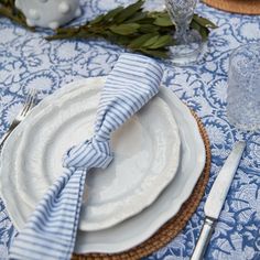 a blue and white table setting with plates, silverware and napkins on it