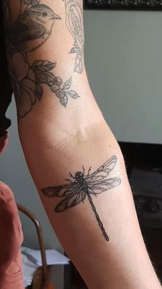 a woman's arm with a dragonfly tattoo on the left side of her arm