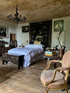 an old fashioned bedroom with antique furniture and paintings on the walls, along with a chandelier