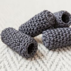 three crocheted gray objects are laying on the bed