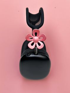 a black purse with a pink flower on the front and back side, against a pink background