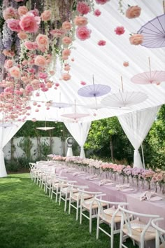 an outdoor wedding setup with pink and purple flowers hanging from the ceiling