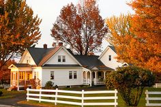 a white house surrounded by trees with fall foliage