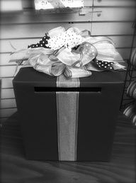 a black and white photo of a gift box with ribbons on it's lid