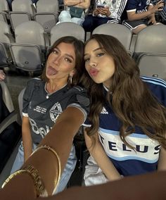 two women sitting next to each other in front of an audience at a sporting event